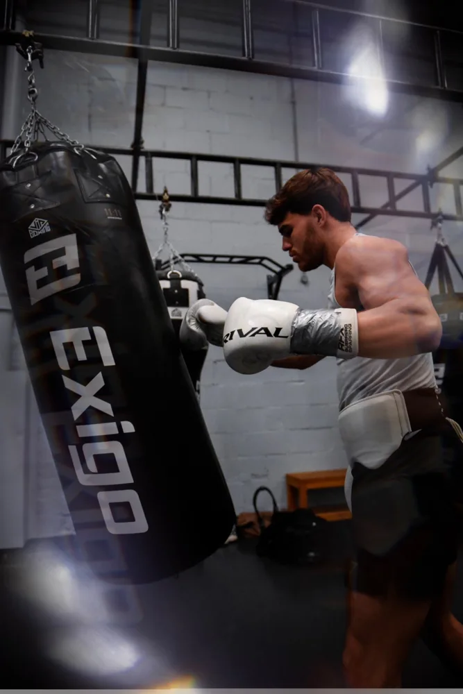 Boxer working a heavy bag in white gloves