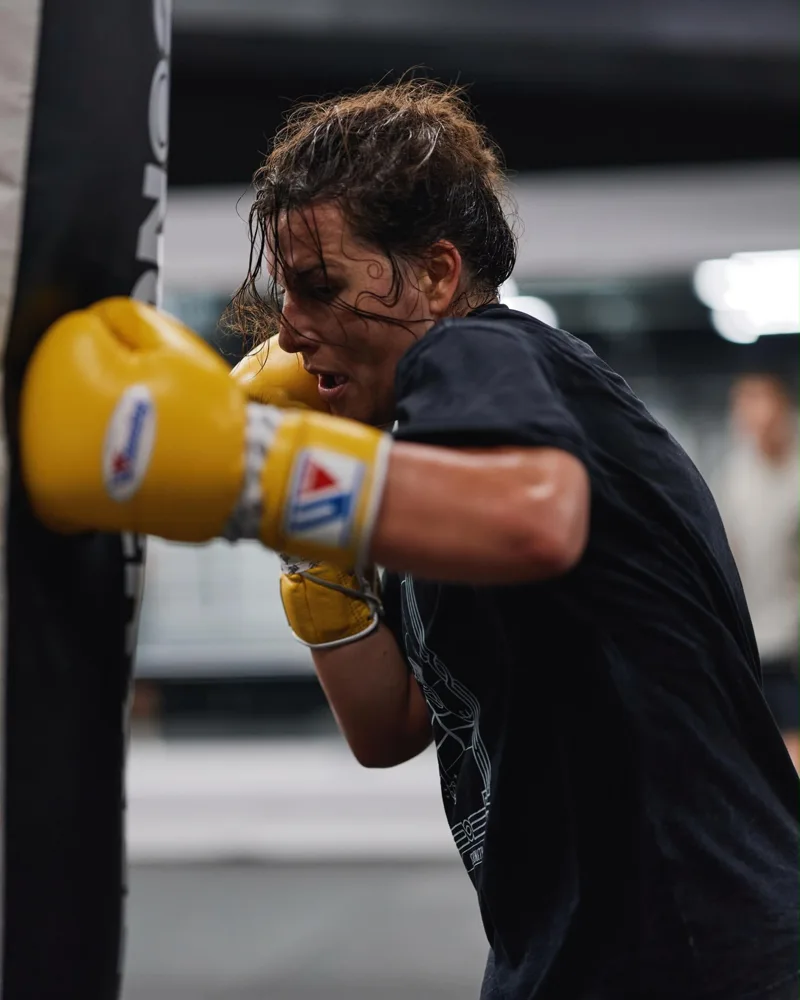 Boxer working a punch bag in yellow gloves