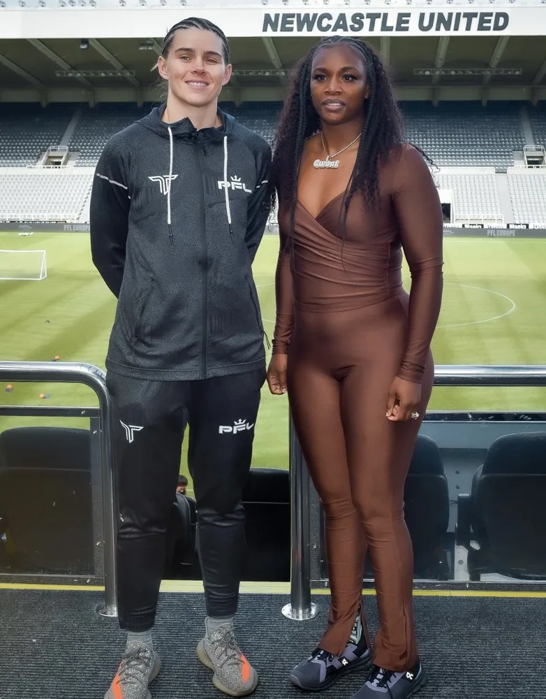 Two athletes posing beside a stadium pitch