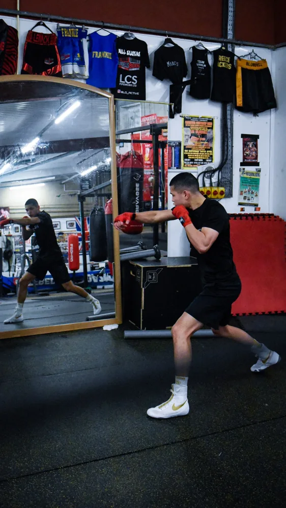 Boxer shadowboxing in front of a gym mirror