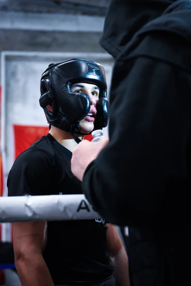 Boxer wearing head protection listening between rounds