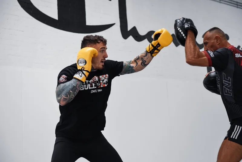 Boxer in yellow gloves working pads with a coach