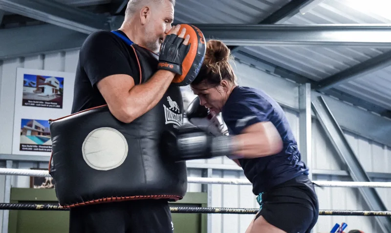 Athlete practising body punches with a coach