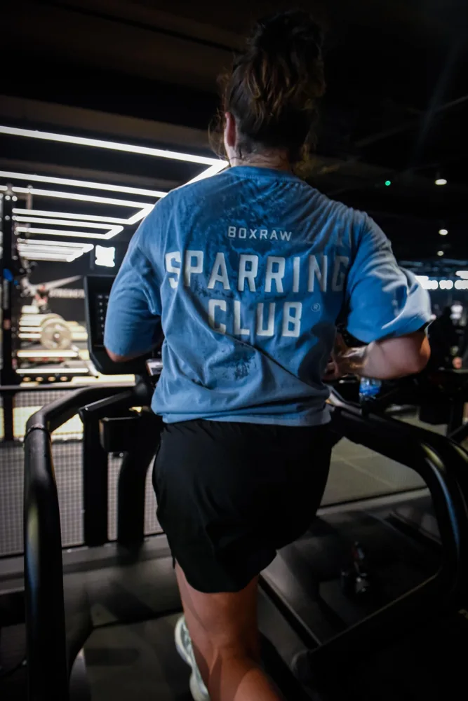 Athlete training on a treadmill in a blue Sparring Club shirt