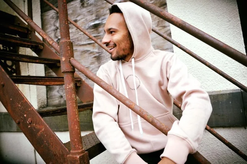 Model wearing a pale hoodie on an industrial staircase