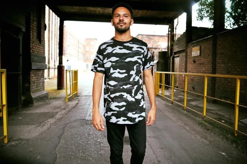 Model wearing a camouflage T-shirt in an industrial setting