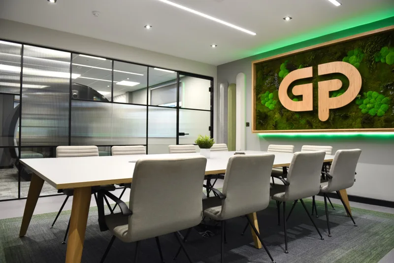 Modern meeting room with a green feature wall and illuminated company logo