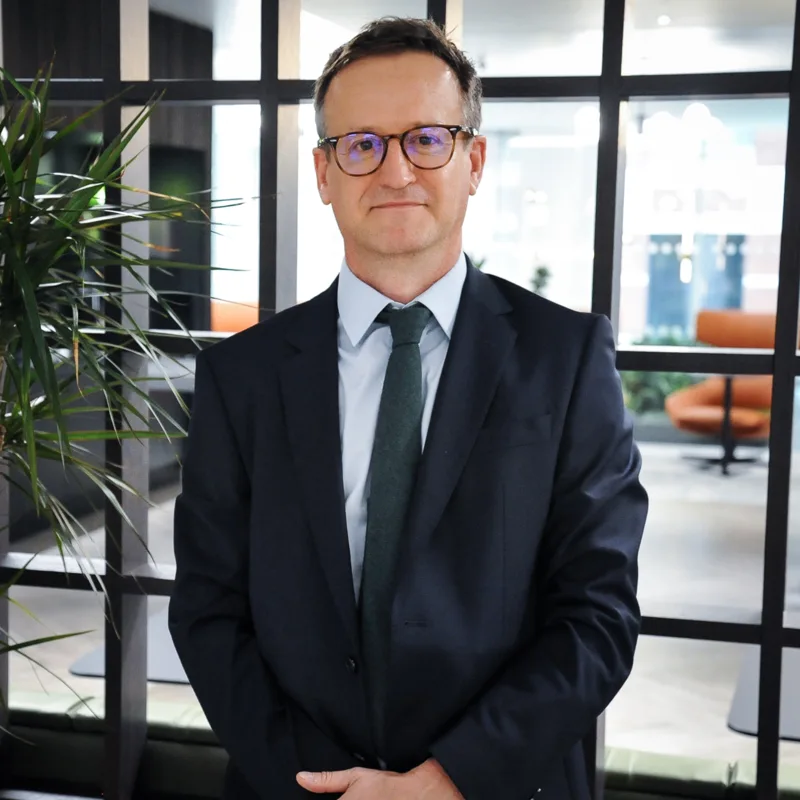 Corporate portrait of a team member in a dark suit and green tie