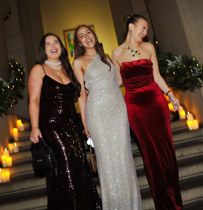 Three guests laughing on candlelit steps in evening dresses