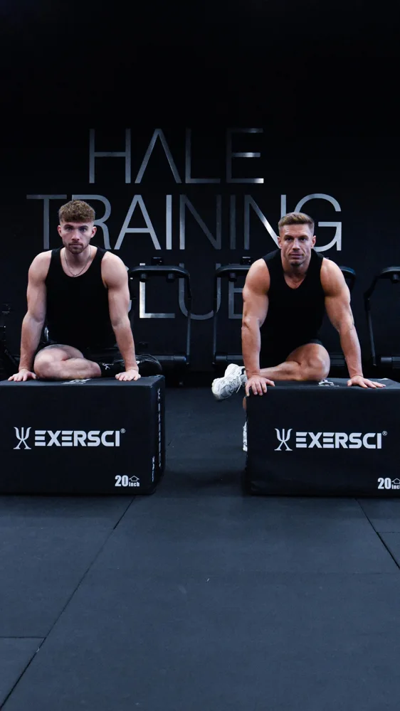 Two men stretching on gym boxes