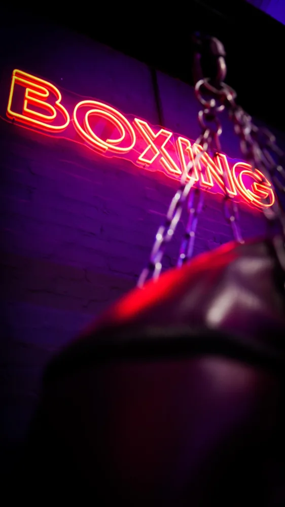Boxing bag beneath a neon sign