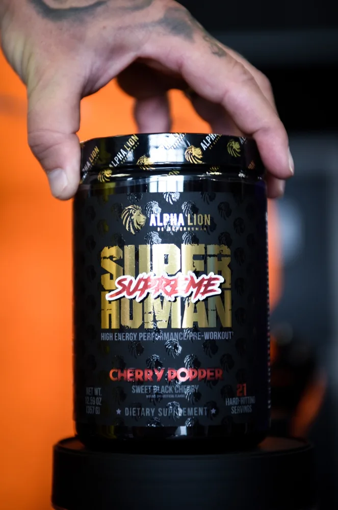 Hand holding a black pre-workout container
