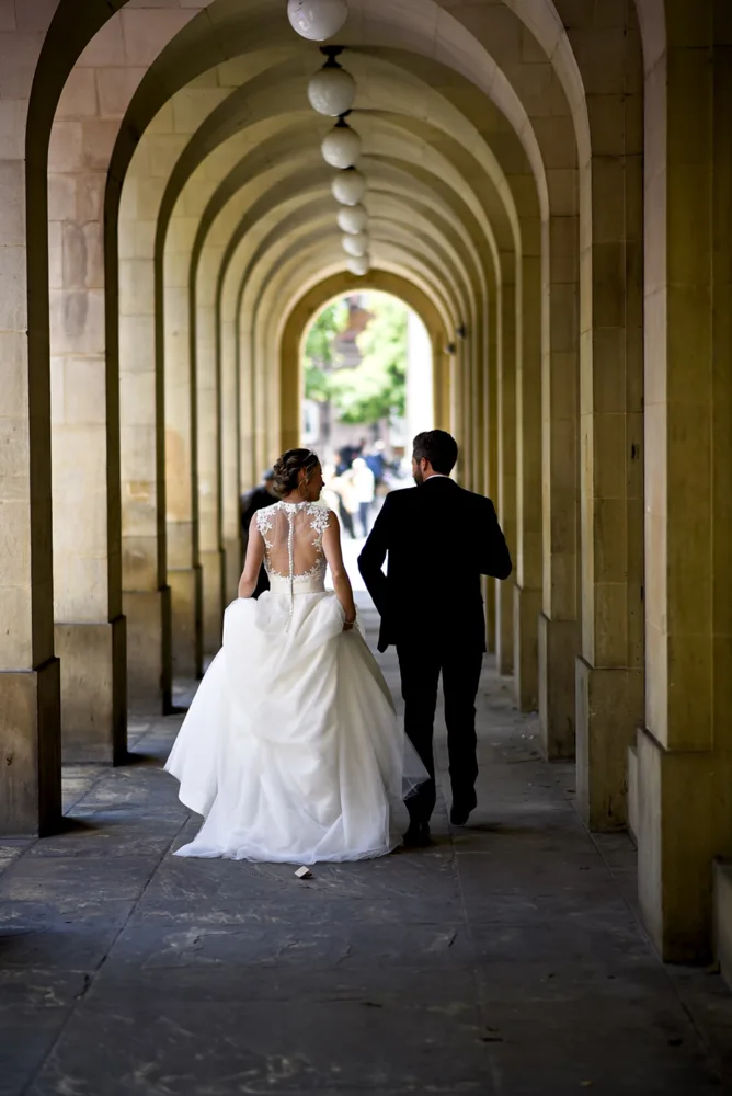 Newlyweds walking beneath stone arches