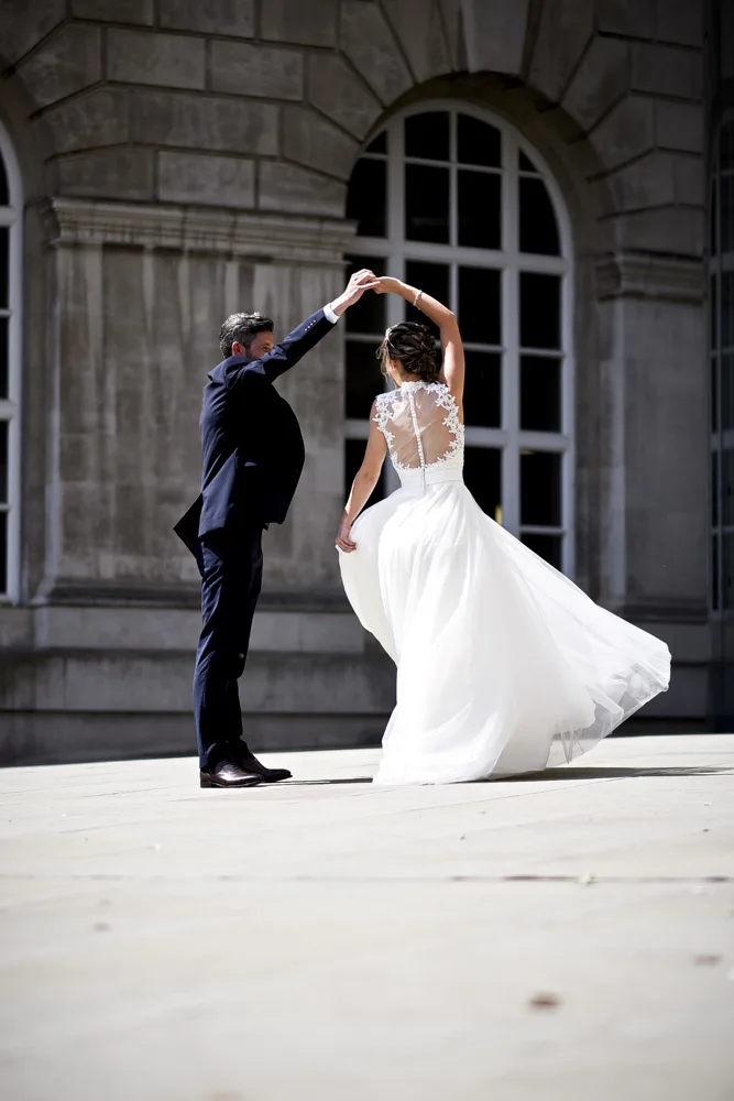 Groom twirling the bride outside a stone building