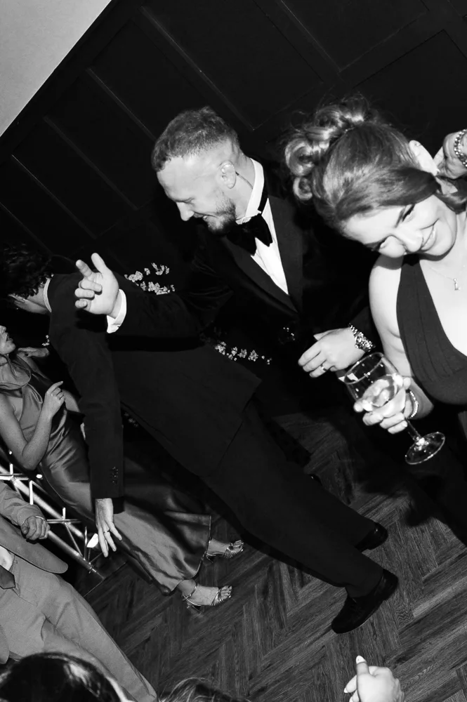 Groom dancing with wedding guests in black and white