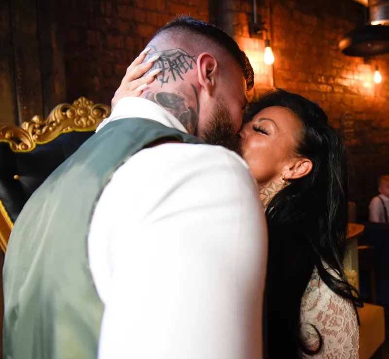 Wedding couple sharing a kiss in a warmly lit venue