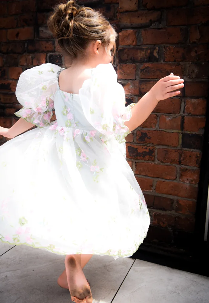 Young wedding guest twirling in a floral dress