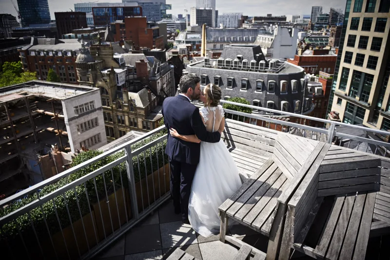 Newlyweds embracing on a rooftop overlooking the city